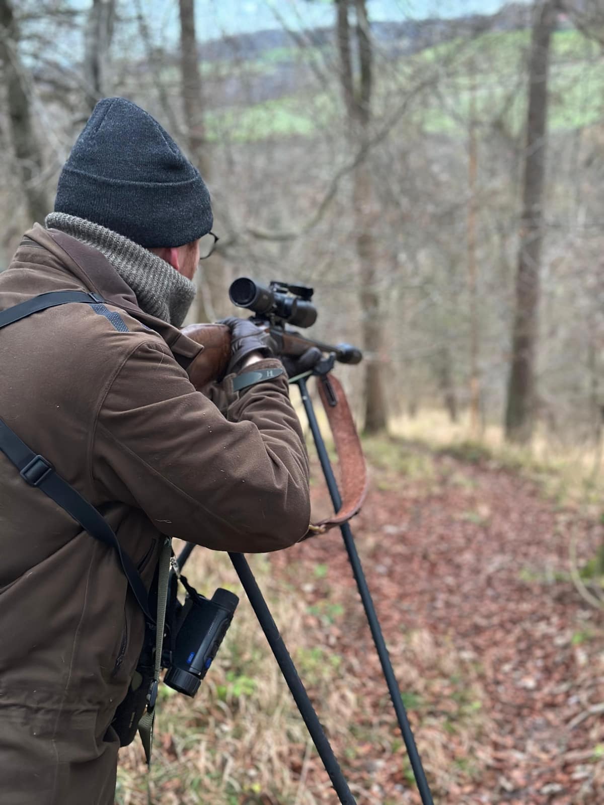 Taking aim from shooting sticks in winter woodland